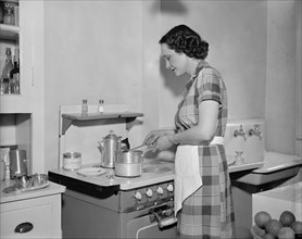A woman cooking on a stove in the kitchen in 1937.