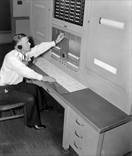 Officer William L. Good is shown at the FBI 'Patrol Board' in the Captain of the Guard's office which maintains direct communication with every watch station and substation throughout the huge FBI Hea...
