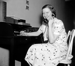 Woman using telephone circa 1937.