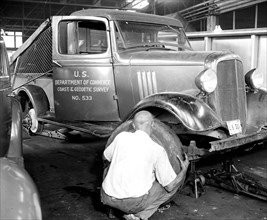 Mechanic changing a tire on a U.S. Government work truck circa 1937.