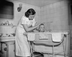Woman giving baby a bath ca.1937.