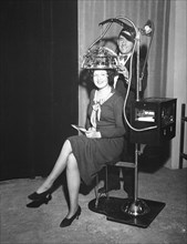 Woman seated with a psychograph, a phrenology machine, on her head circa 1931.