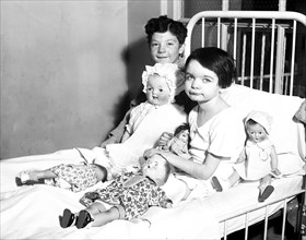 Children in bed with dolls; in hospital? circa 1931.
