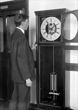 Chester Burleigh Watts turning back the hands of a clock at the Naval Observatory in 1918 (possibly in honor of the first Daylight Savings Time) .