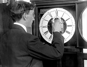 Chester Burleigh Watts turning back the hands of a clock at the Naval Observatory in 1918 (possibly in honor of the first Daylight Savings Time) .