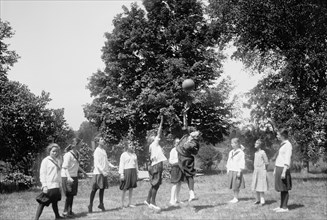 Young girls playing a game outdoors at a YWCA camp (Young Woman's Christian Association) circa 1919.