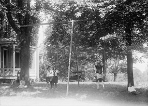 Children having fun and playing on a swing set at a YWCA camp circa 1919 .