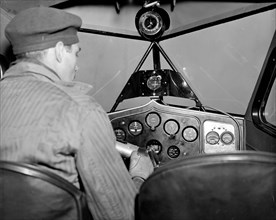 Pilot in a cockpit making a blind landing in a plane  circa 1937 .