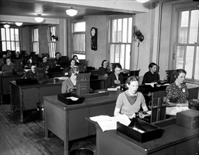 Women sitting behind desks working in a stenographers pool circa 1937.