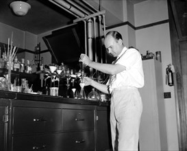 Testing cosmetics at Department of Agriculture Washington D.C. July 10. Dr. D.C. Grove, of the Dept. of Agriculture is shown giving a shakedown test of different creams circa 1937.