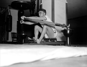 Historical Exercise - Man using a rowing machine circa 1937 .