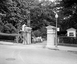 Workers helping to erect new gates at west entrance to White House to prevent careless and tipsy drivers from crashing through circa 1937.