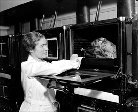A woman demonstrates how to correctly cook a turkey circa 1937.