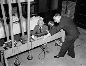 Government Waste - Bureau of Standards designs mechanical batter to determine liveliness of baseballs, an example of government wasting money during the Great Depression circa 1938 .