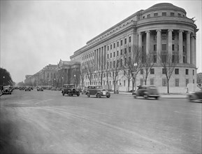 Cars in street scene in Washington D.C. outside government APEX building circa 1938.