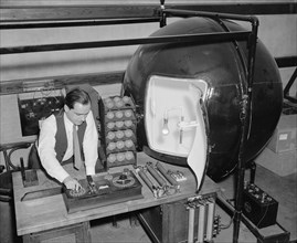 Government worker testing the amount of light given off by lightbulbs circa 1938.
