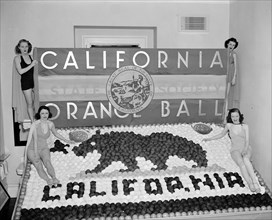 Women posing with California orange week festival ball display circa 1938.
