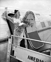 Miss Marion Weldon, Paramount starlet, waves a greeting to the throng as she arrived at Washington Airport today to participate in National Airmail Week circa 1938.