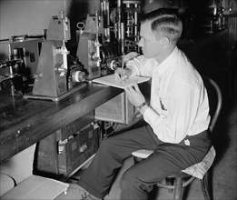 A National Bureau of Standards worker conducting experiement to help with movie film preservation - folding endurance test circa 1938.