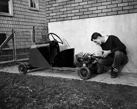 16 year old boy with his home made go kart powered by a washing machine motor circa 1939 .