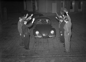 Men wave hello to the 'first volkswagen' (original caption) circa October 16, 1947.