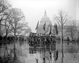 Thousands braved a heavy rain today to witness the Army Day parade pass the U.S. Capitol - here, soldiers present the colors, the flags, to parade watchers circa 1939.