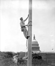 Worker painting flag pole of senate office building in Washington D.C. circa 1939.