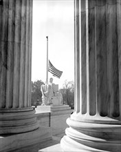 Scene thru the pillars of the U.S. Supreme Court Building showing the flag at half-mast out of respect to Justice Pierce Butler, who died this morning after a long illness circa November 1939 .