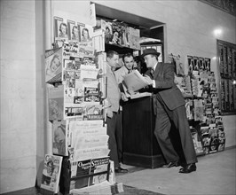 Customer and workers at newstand in the National Press Building circa 1940.
