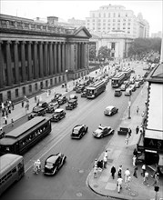 Pedestrians, cars and street cars near Treasury Department on 15th Street in Washington D.C. circa 1936.