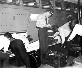 Workers at Greyhound bus station loading and checking baggage circa 1937.
