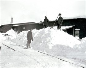 Three men shovelling snow from the railway tracks outside the car works in Deseronto, Ontario, taken in February 1908.