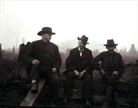 Three men sitting on some logs. Photograph taken September 1908 at Lake St. Peter, Ontario..