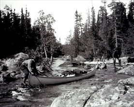 Two men manoeuvering a canoe down a set of rapids, possibly on the Lady Evelyn River, Ontario circa 1909.