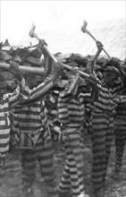 African American convicts working with axes and singing in woodyard, Reed Camp, South Carolina circa 1934.