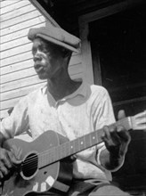 Bill Tatnall, half-length portrait, seated, facing left, playing guitar, Frederica, Georgia circa June 1935.