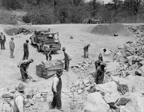 Prisoners breaking up rocks at a prison camp or road construction site circa 1934-1950.