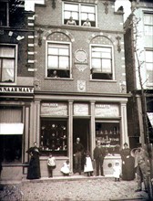 Merchant and other people outside of a business in Alkmaar Netherlands circa 1900.