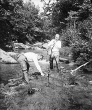 Two men fishing in a river circa 1932.