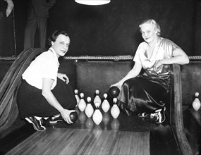 Women in a bowling alley holding balls by the pins circa 1936.