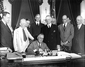 Franklin D. Roosevelt - President Roosevelt with members of congress looking on as he signs a banking bill in 1933 .