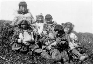 Edward S. Curits Native American Indians - Photograph shows six Nunivak children dressed in fur, sitting on hill circa 1929 .