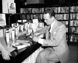 Author Erskine Caldwell signing copies of book 'Tobacco Road' circa April 1936.