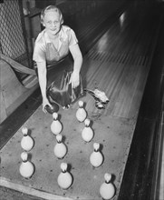 Woman in a bowling alley holding ball by the pins circa 1936.