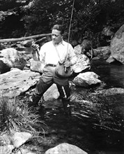 A man fishing in a river circa 1932.