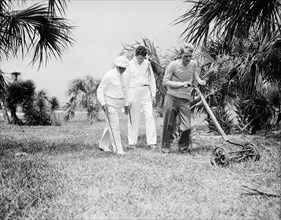 Golfers mowing the rough after hitting their golf ball into it and losing the ball circa 1935.