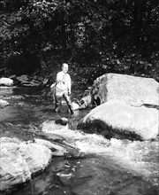 A man fishing in a river circa 1932.