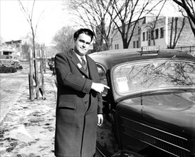 Man pointing at heated taxi cab from the Yellow Cab company circa 1936.