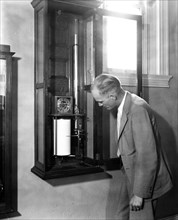Man with a recording mercurial barograph, an instrument made and perfected by the U.S. Weather Bureau which measures, on a magnified scale, the fluctuations in the pressure of the air circa 1936.