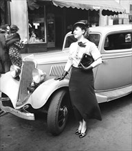 Woman standing outside of an automobile (car) circa 1935.